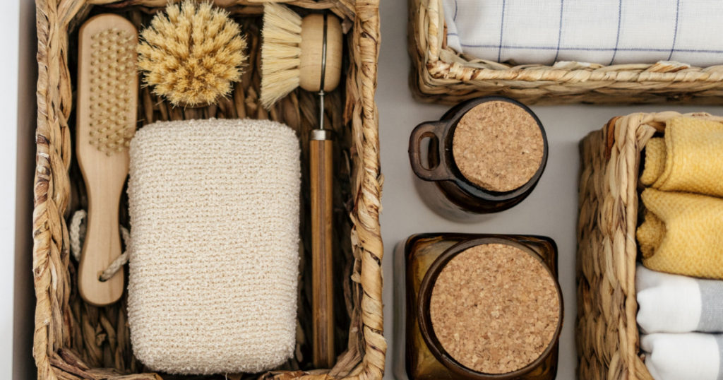 Flat lay view of zero waste products inside organization boxes and wicker baskets. Open drawer at kitchen closet with washing dishes items, bamboo brushes, eco friendly sponge and textile towel 