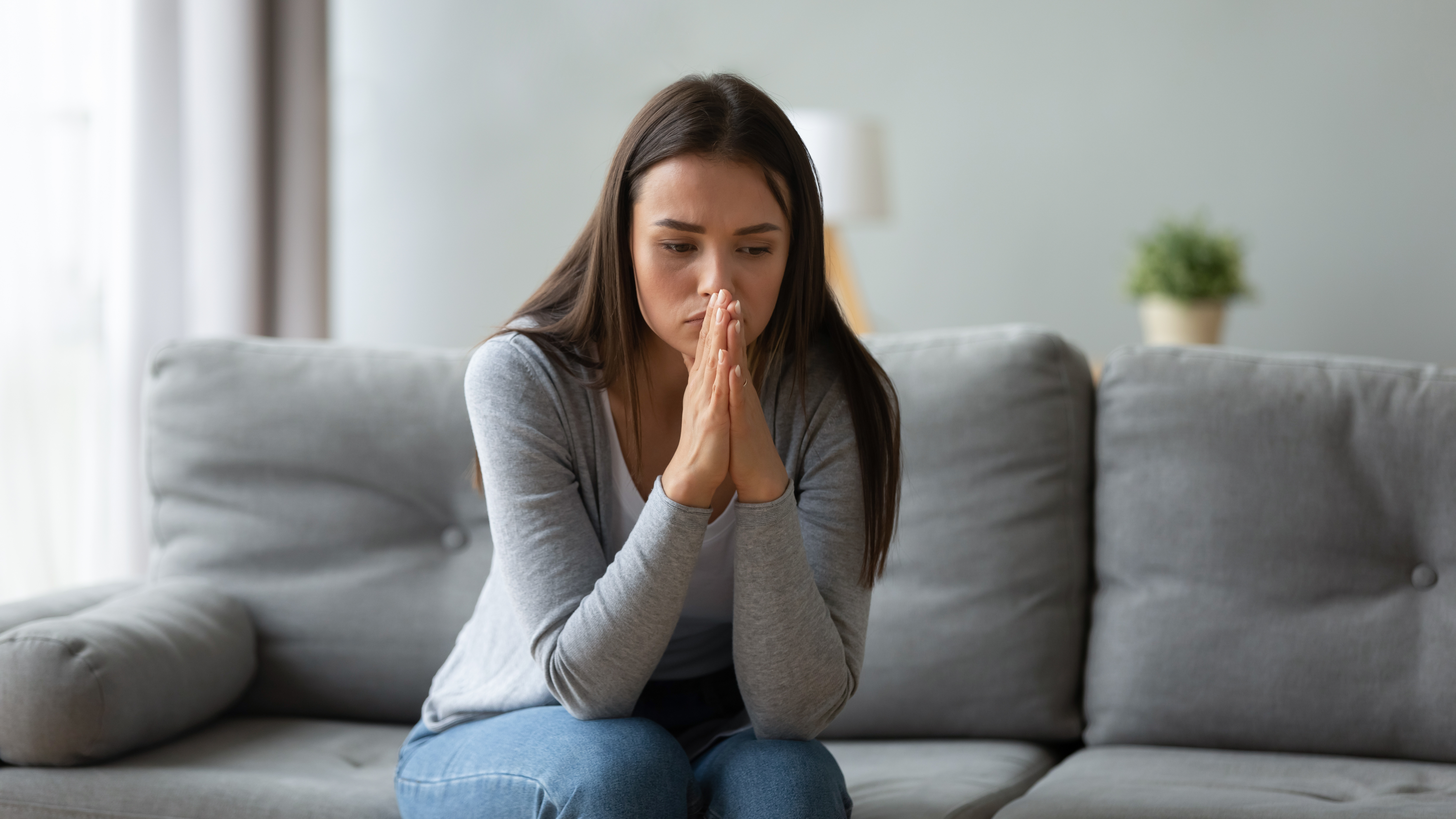 A distraught woman sitting on the sofa | Source: Shutterstock