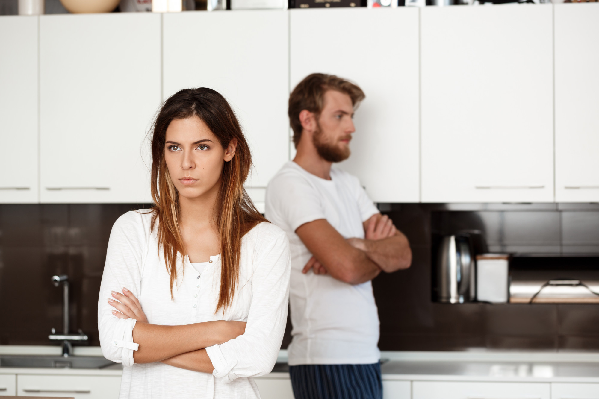 A displeased couple standing in a kitchen | Source: freepik.com