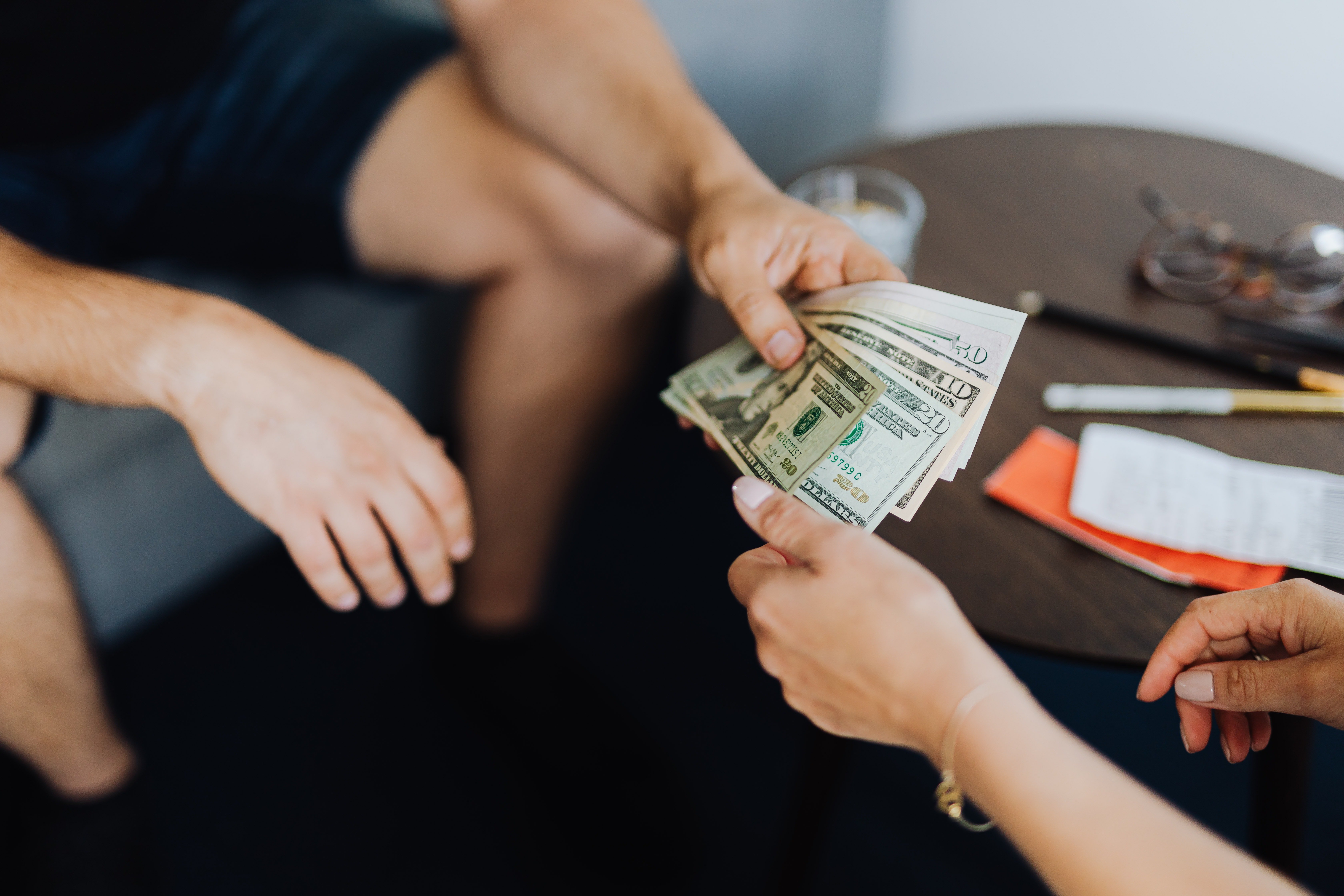 Man handing dollar notes to a woman | Source: Pexels