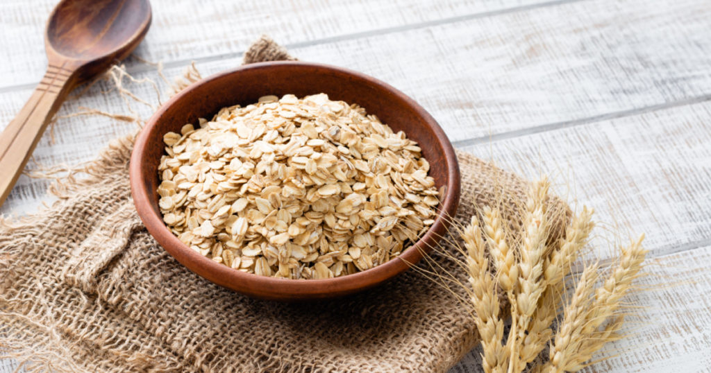 Rolled oats, healthy breakfast cereal oat flakes in bowl on wooden table 