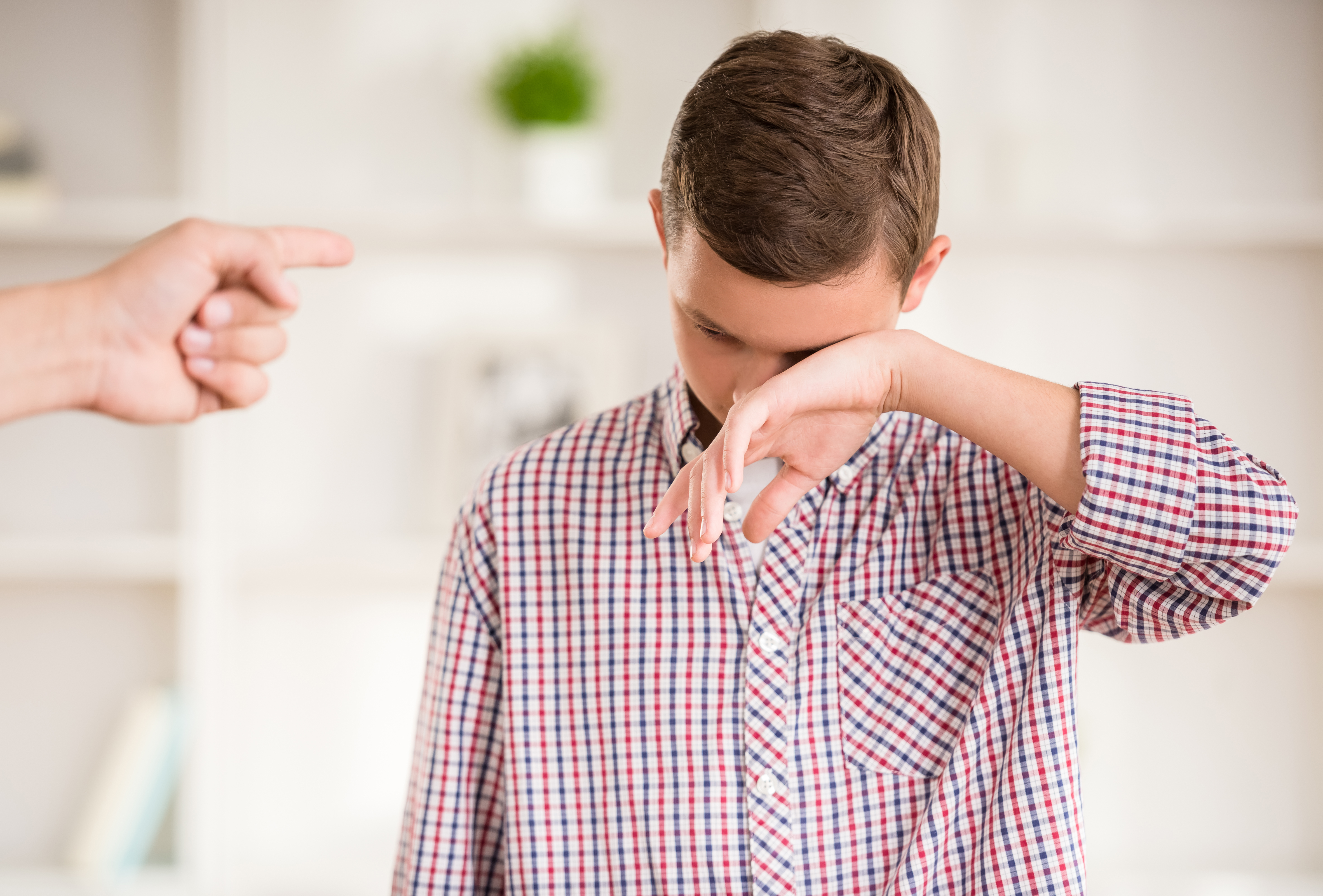 A boy appearing to cry as a finger is pointed at him | Source: Shutterstock