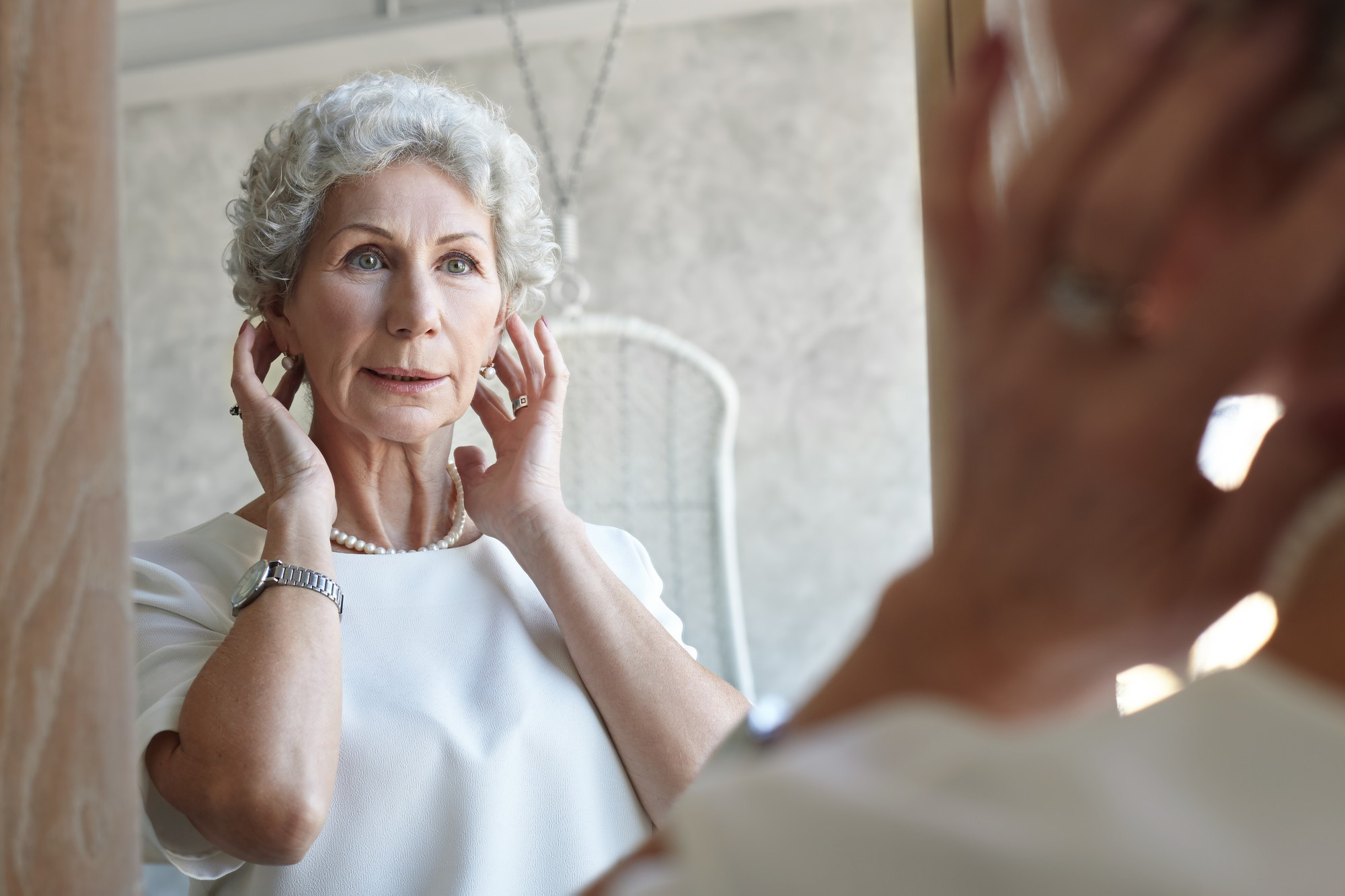 An older woman looking at herself in the mirror | Source: freepik.com