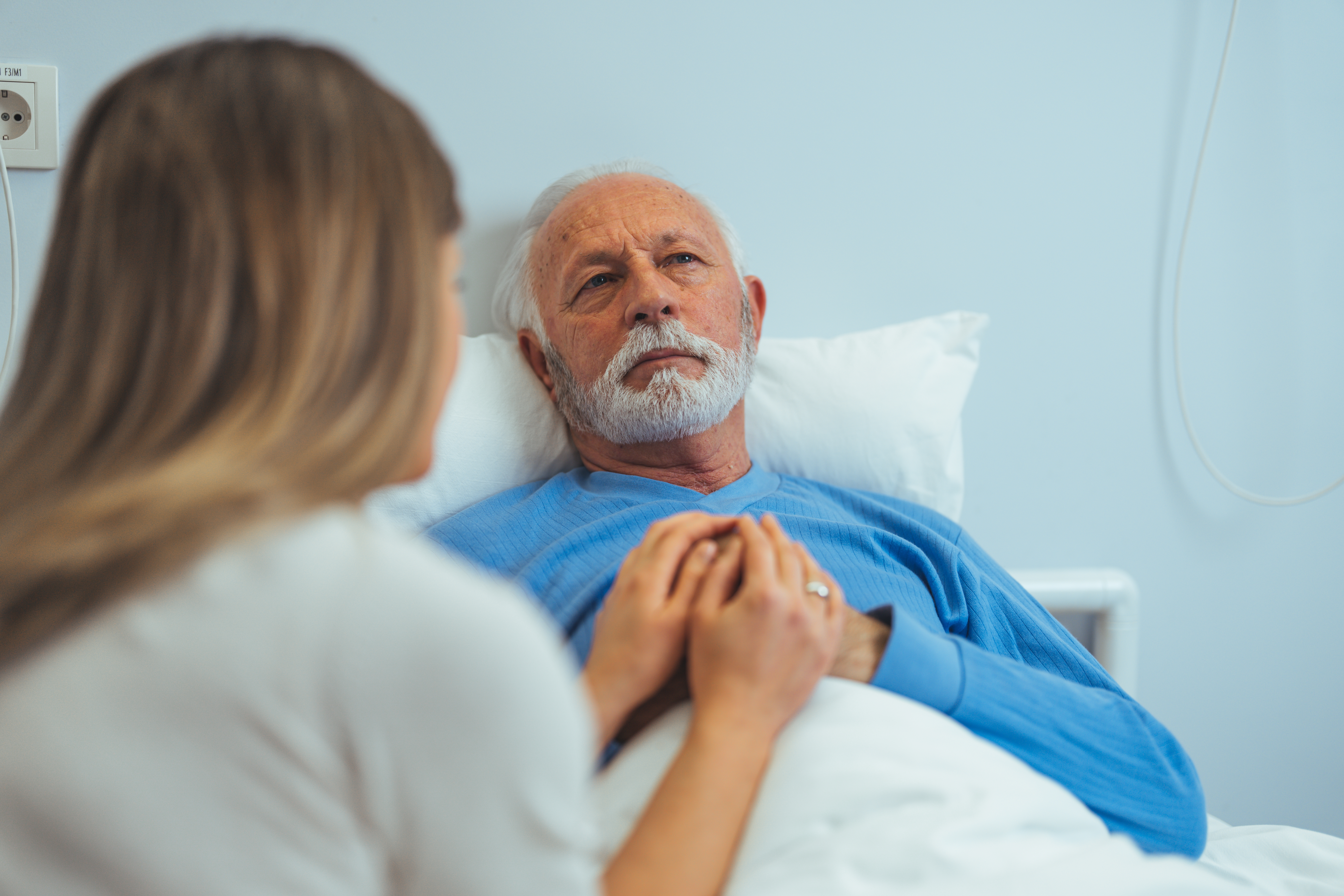 A young woman comforting her ill father in the hospital | Source: Shutterstock