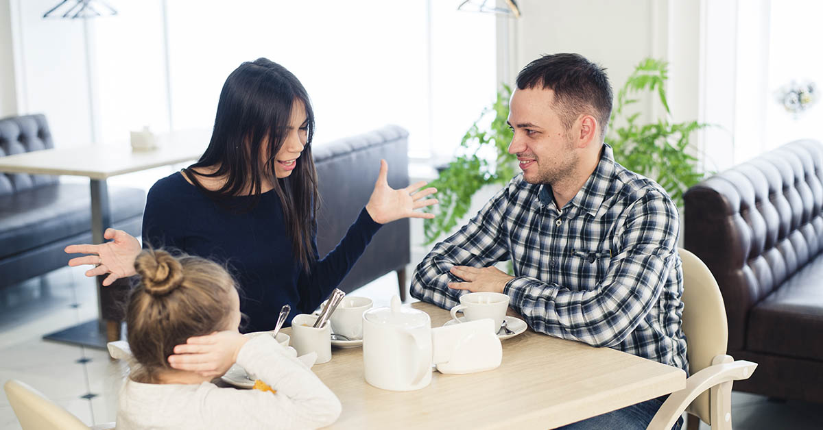 Two parents and their child sitting down in restaurant