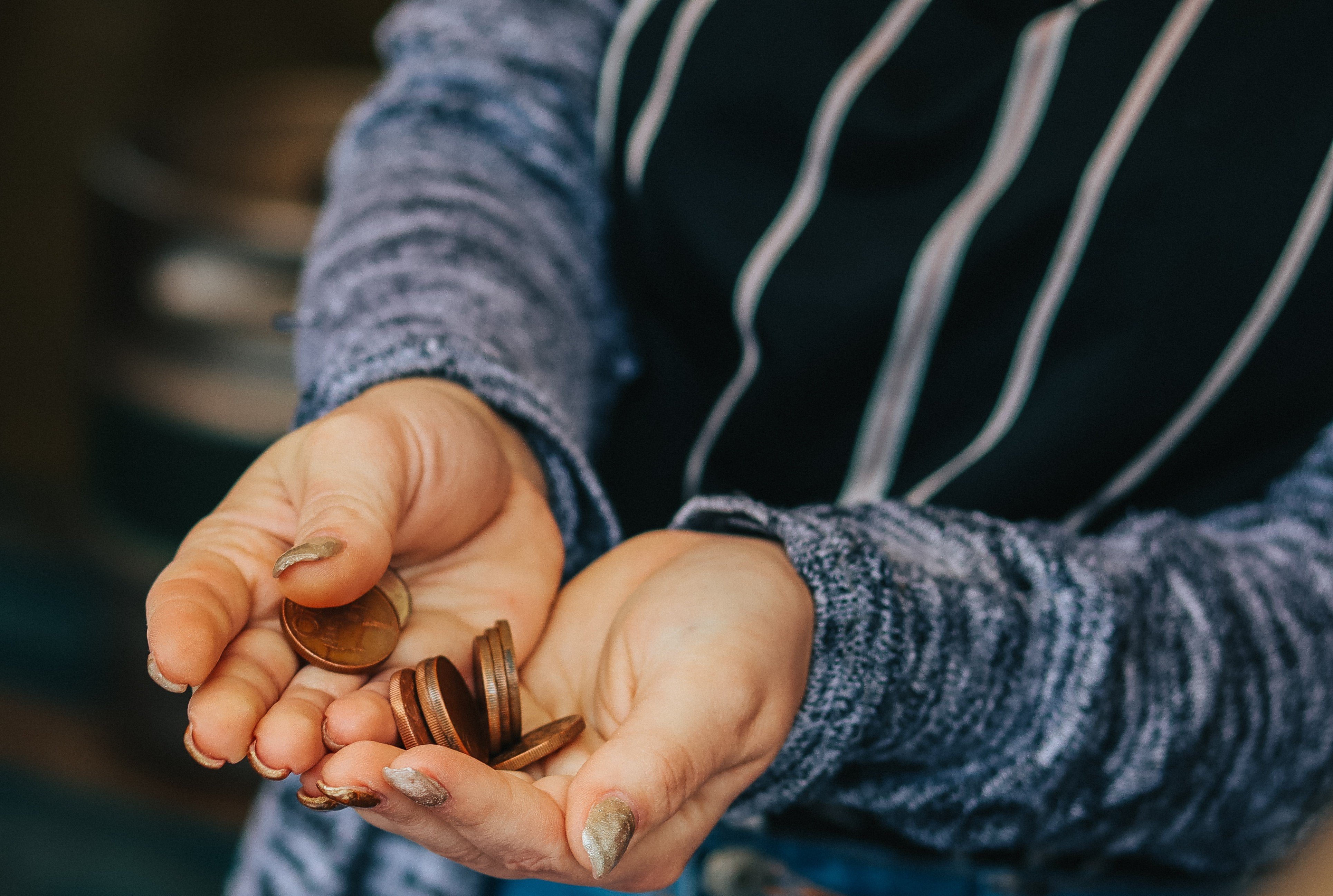 A woman holding coins in her hands | Source: Pexels